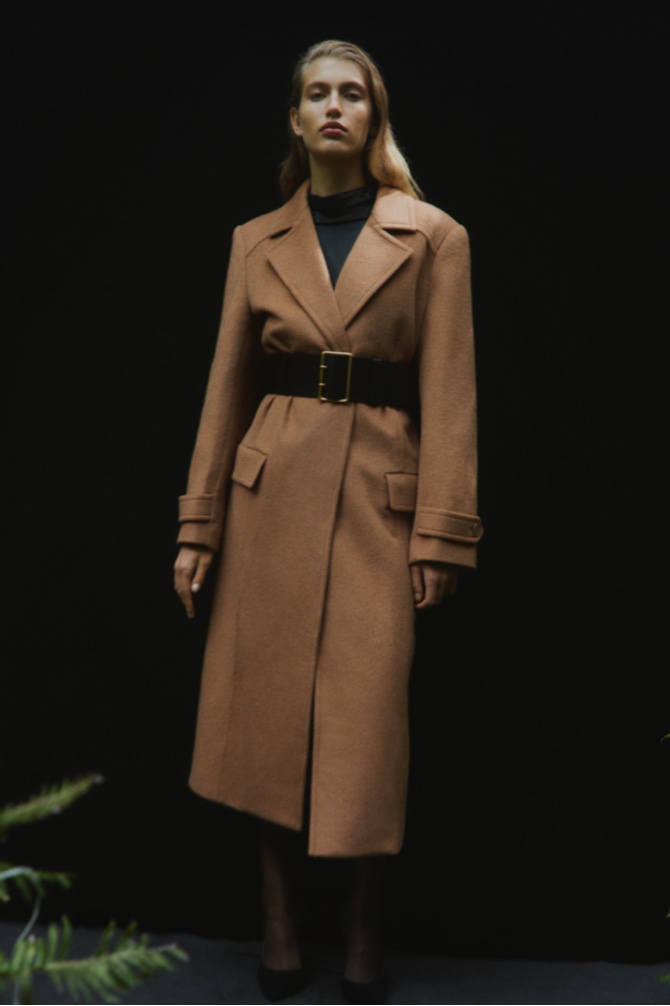 Woman in the golden brown wool cashmere tie coat, black drape neck long sleeve blouse and black wide fastened belt