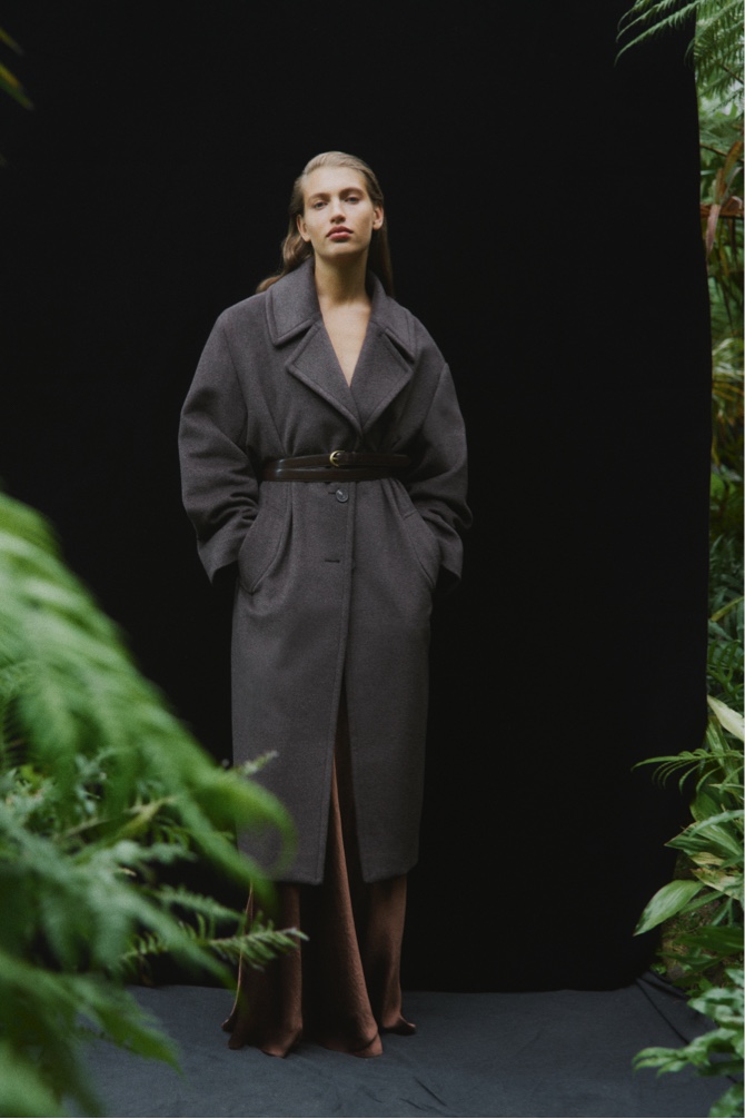 Woman in ice grey wool cashmere lapel coat, dark cocoa bias acetate maxi skirt and syrup brown double wrap belt