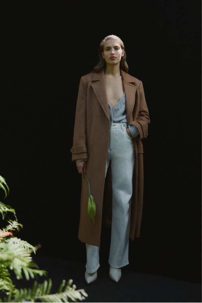 Woman in golden brown wool cashmere tie coat, light grey marle tactile knit cardigan and ecru pinstitch slim jean