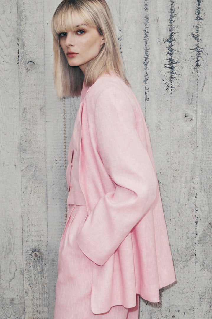 Woman in floss pink linen double breasted blazer, floss pink linen split detail shirt and floss pink linen pleat pant