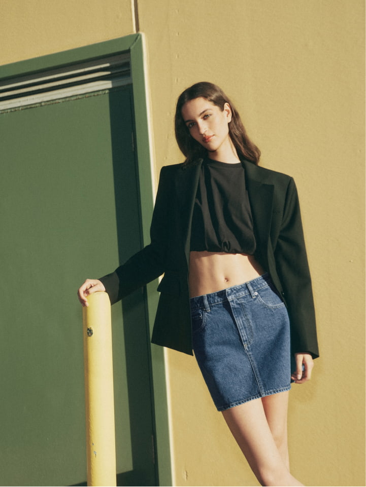 Woman wearing the black oversized single breasted blazer, black crop gather tank and indigo denim mini skirt
