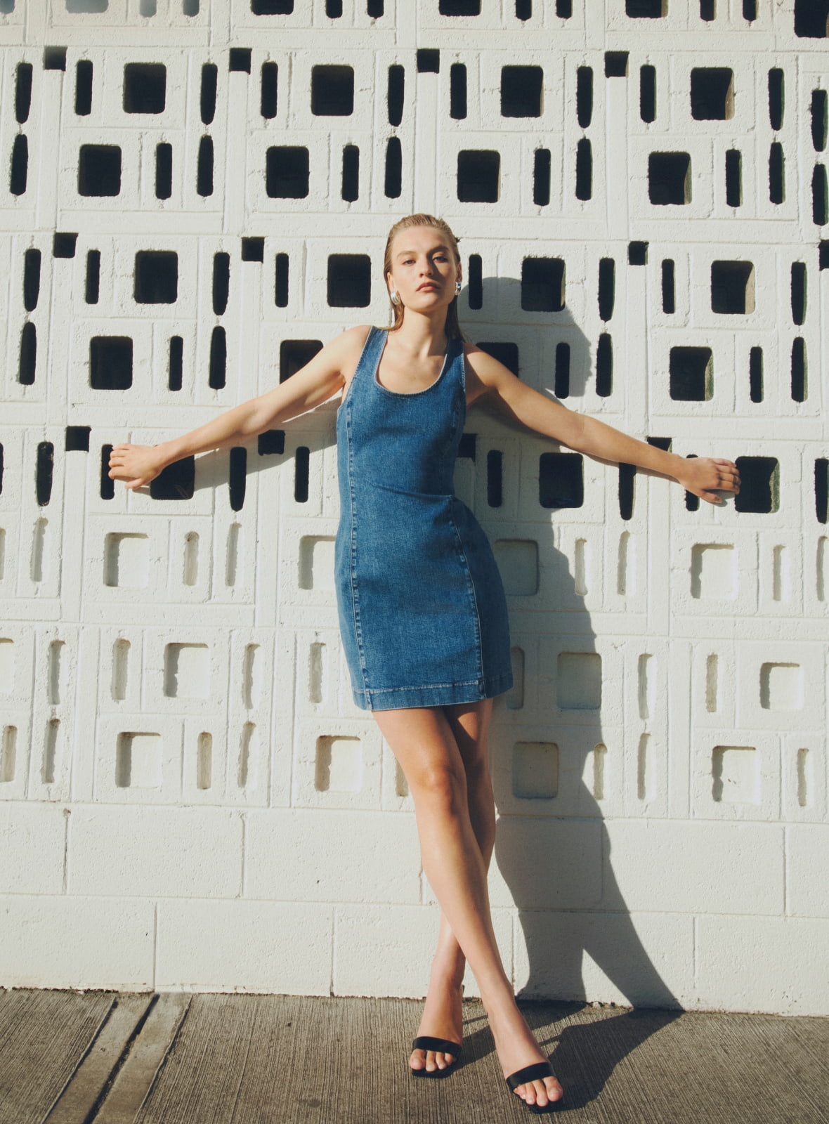 Woman in denim mini dress and black grace mule