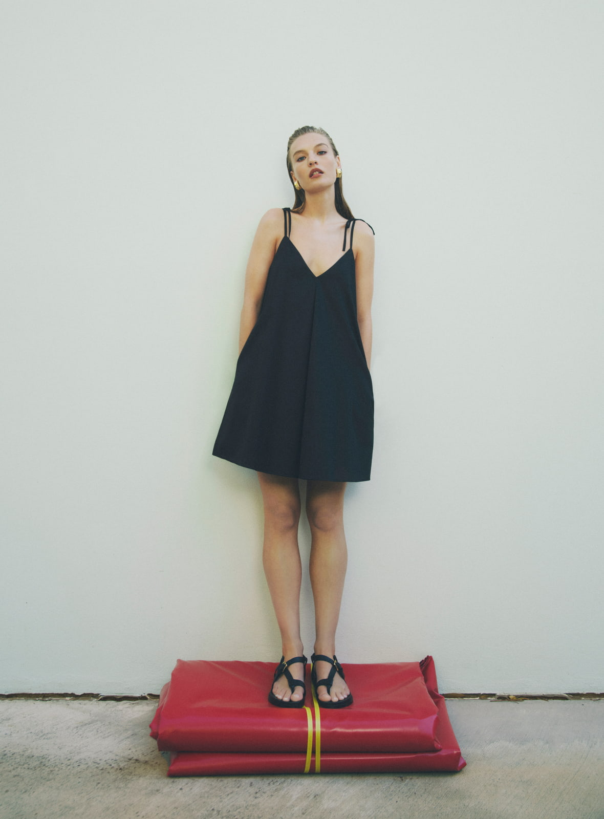 Woman in black invert pleat mini dress and black billie sandal