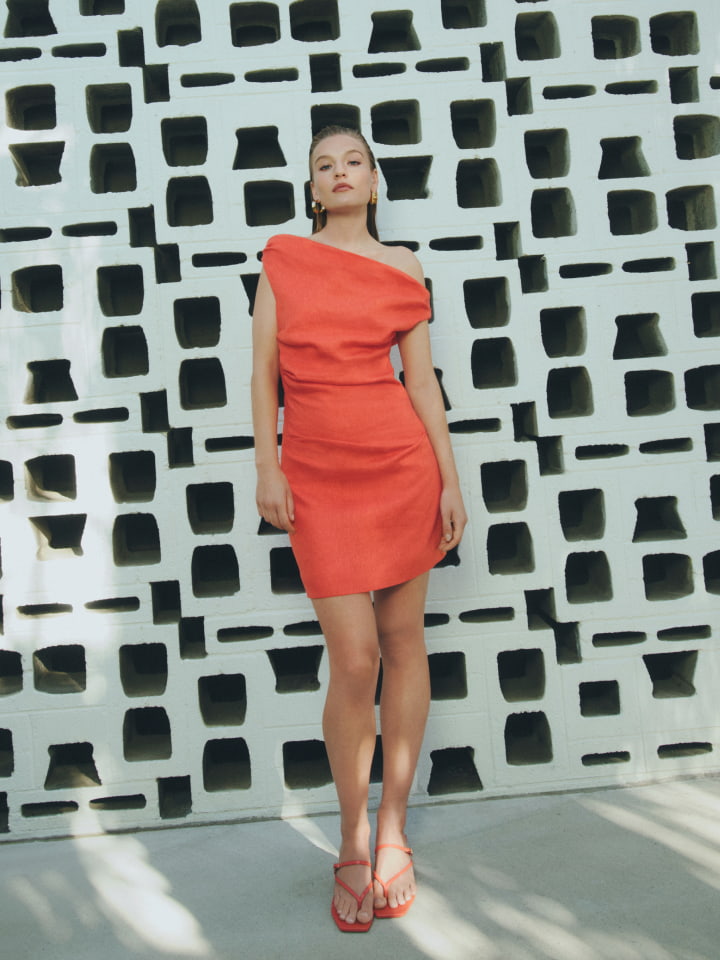Woman in tangerine off shoulder mini dress and tangerine alexis mule