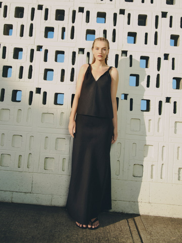 Woman in black twist strap camisole, black bias linen skirt, black jade sandal and silver zahra drop earring