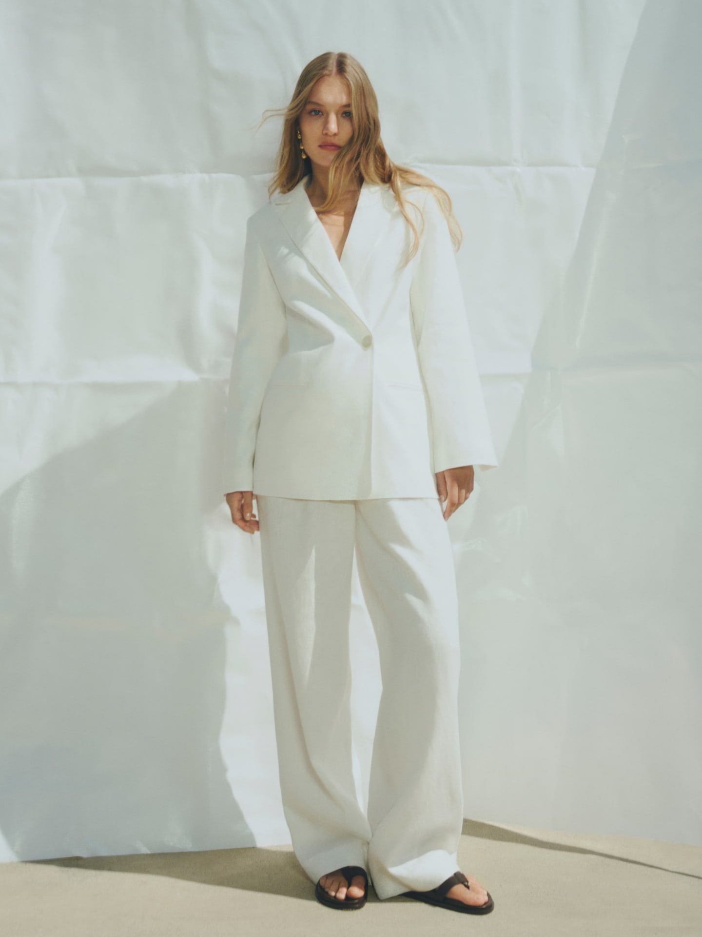 Woman in white linen double breasted blazer, white high rise pant and black jade sandal