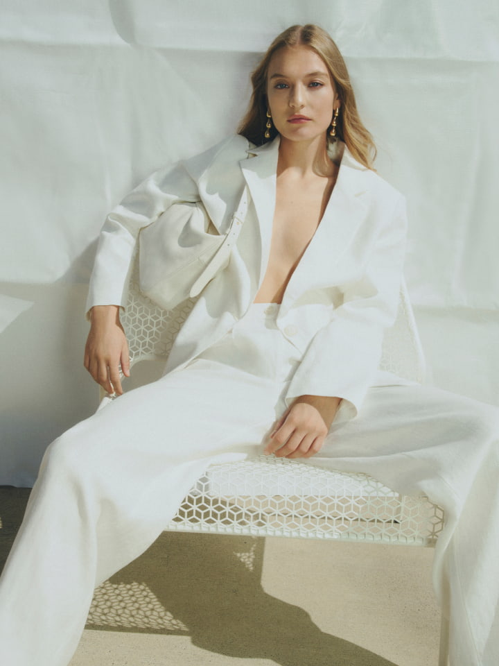 Woman in white linen double breasted blazer, white high rise pant and silver zahra drop earring