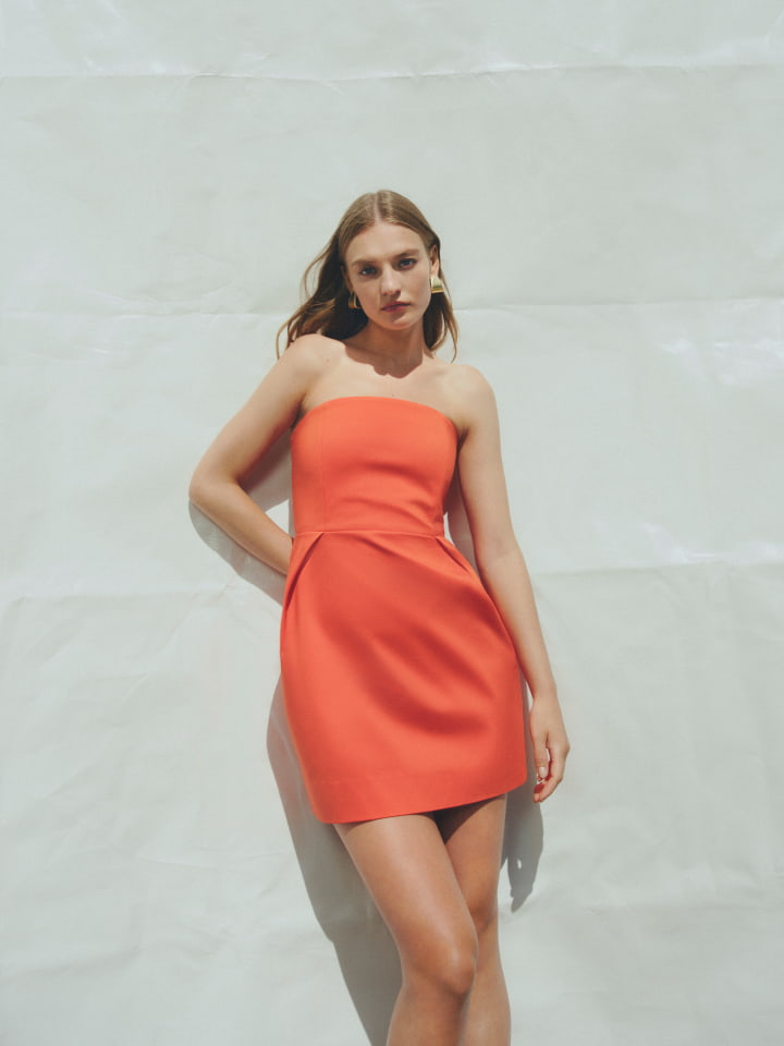 Woman in tangerine strapless mini dress and gold lacey large earring