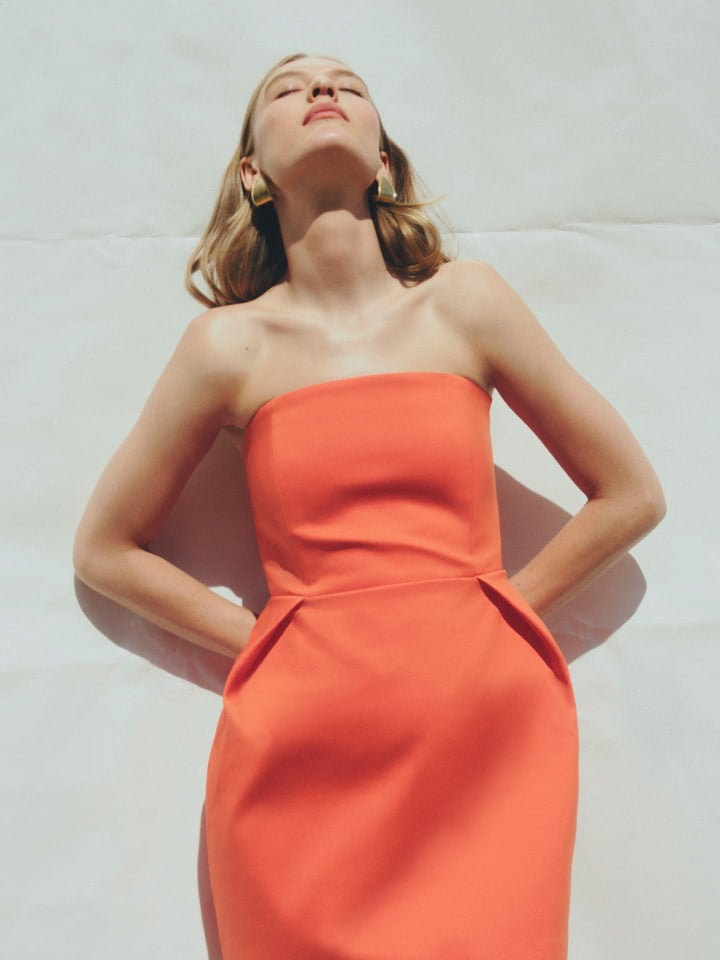 Woman in tangerine strapless mini dress and gold lacey large earring